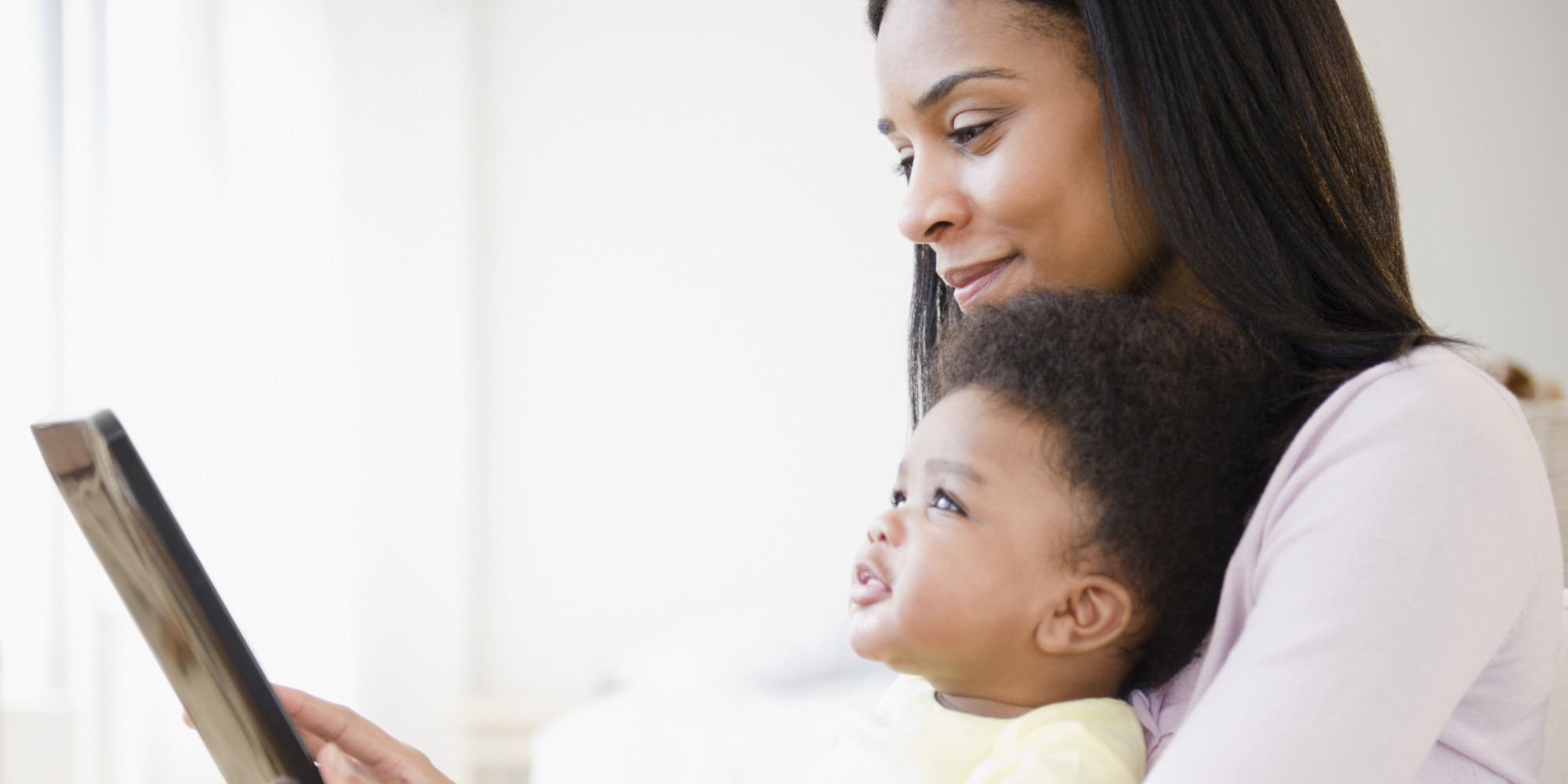African American mother showing digital tablet to baby boy